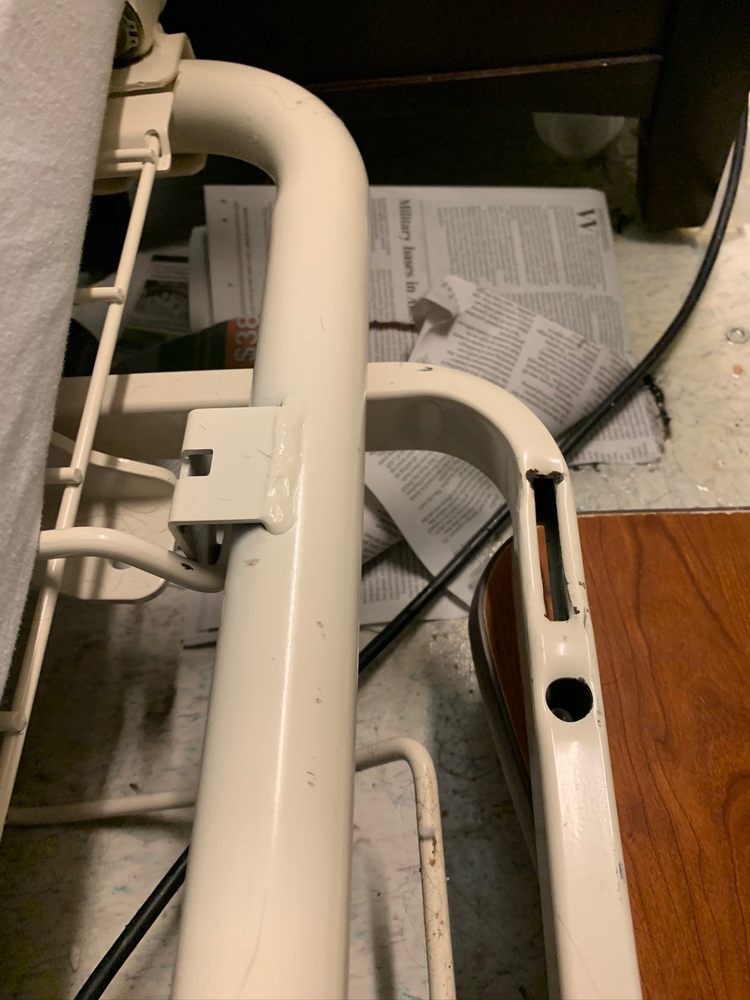 A broken metal bed frame with visible damage indoors.