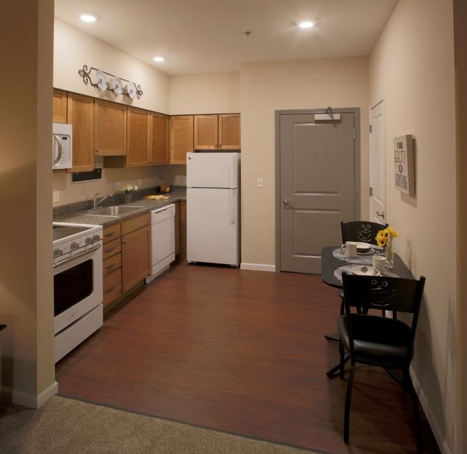 A cozy apartment kitchen with wooden cabinets and a small dining area.