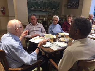 A group of seniors engaging in a lively discussion over a meal.