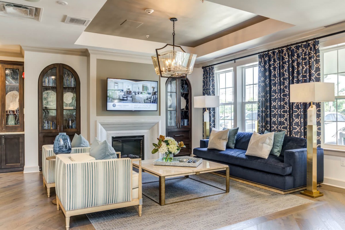 A stylishly designed living room featuring a comfortable seating area, elegant chandelier, and a cozy fireplace.