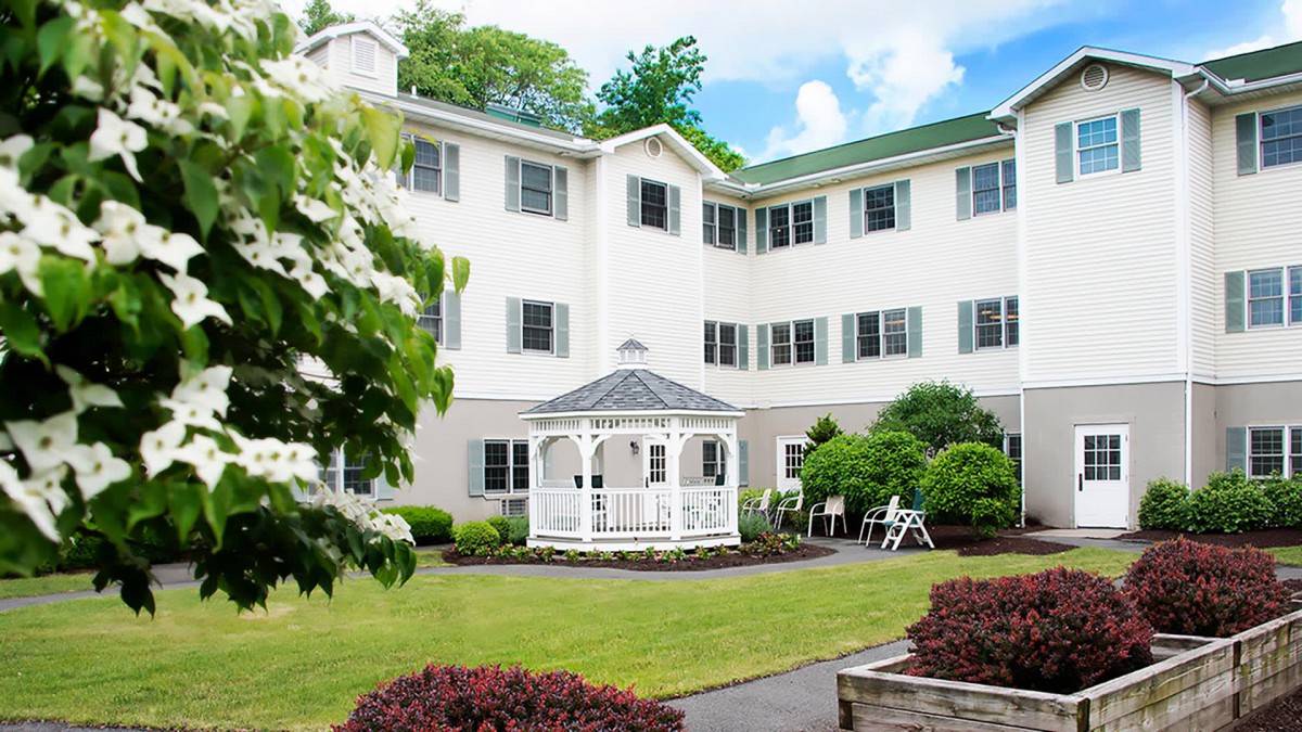 A well-maintained garden with a gazebo in front of a multi-story building.