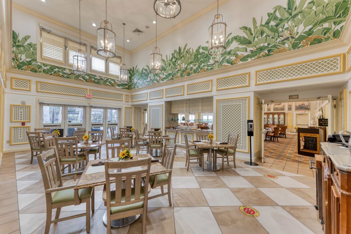 A beautifully decorated dining area with wooden tables and chairs, adorned with hanging lights and greenery.