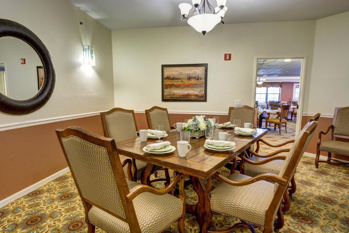 A formal dining room with an elegant table setting and classic wooden chairs.
