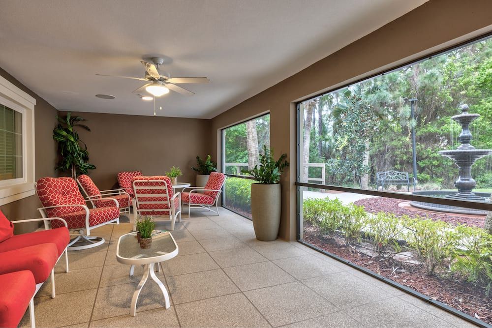 A cozy indoor-outdoor patio with comfortable seating and large windows overlooking a garden.