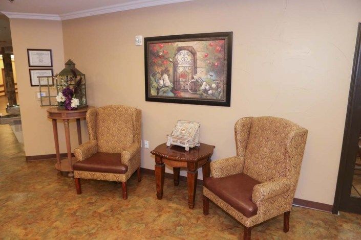A cozy seating area with two upholstered chairs, a table, and a decorative painting on the wall.
