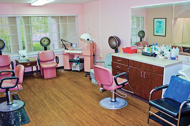 A cozy hair salon with pink decor, equipped with styling stations and hair dryers.