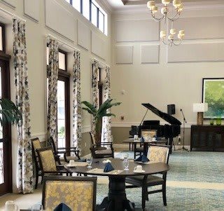 Elegant dining area with a grand piano and large windows.