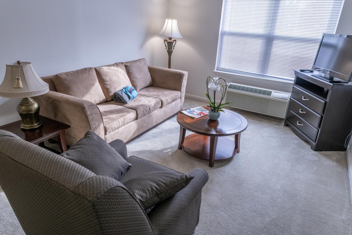 A cozy living room with a sofa, armchair, lamp, and coffee table.