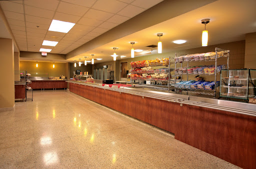 A well-lit cafeteria featuring a long serving counter with various food options available.