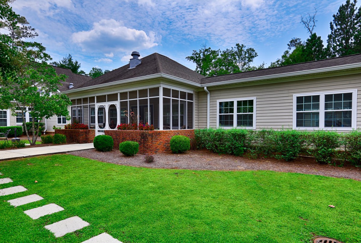 A beautiful backyard with a well-maintained lawn and a cozy screened porch.
