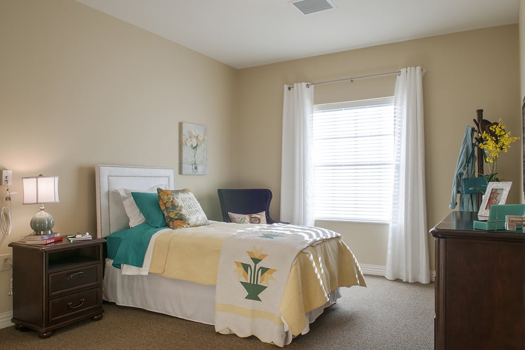 A cozy and well-decorated bedroom with a neatly made bed, accent pillows, and natural light coming through the window.