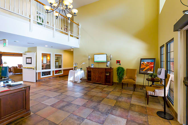 A spacious lobby with a chandelier, tile flooring, and comfortable seating.