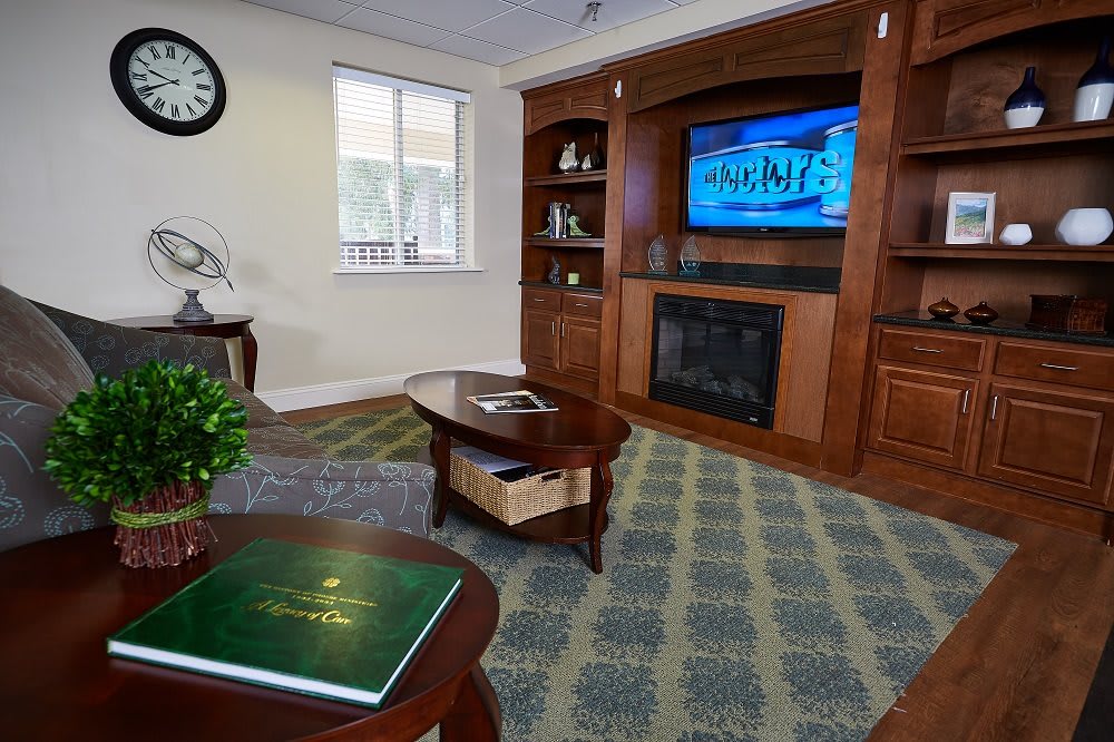 A cozy living room featuring a fireplace, television, and wood-paneled bookshelves.