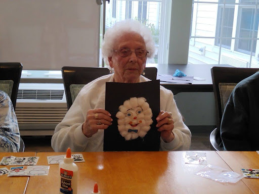 An elderly individual proudly displaying their artistic creation during a craft session.