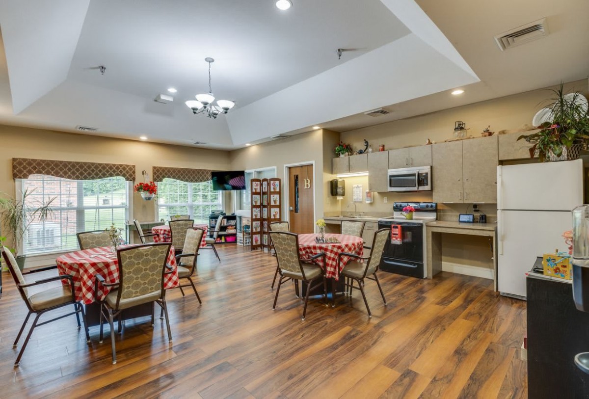 A modern kitchen and dining area with hardwood floors, featuring tables and chairs set for dining.
