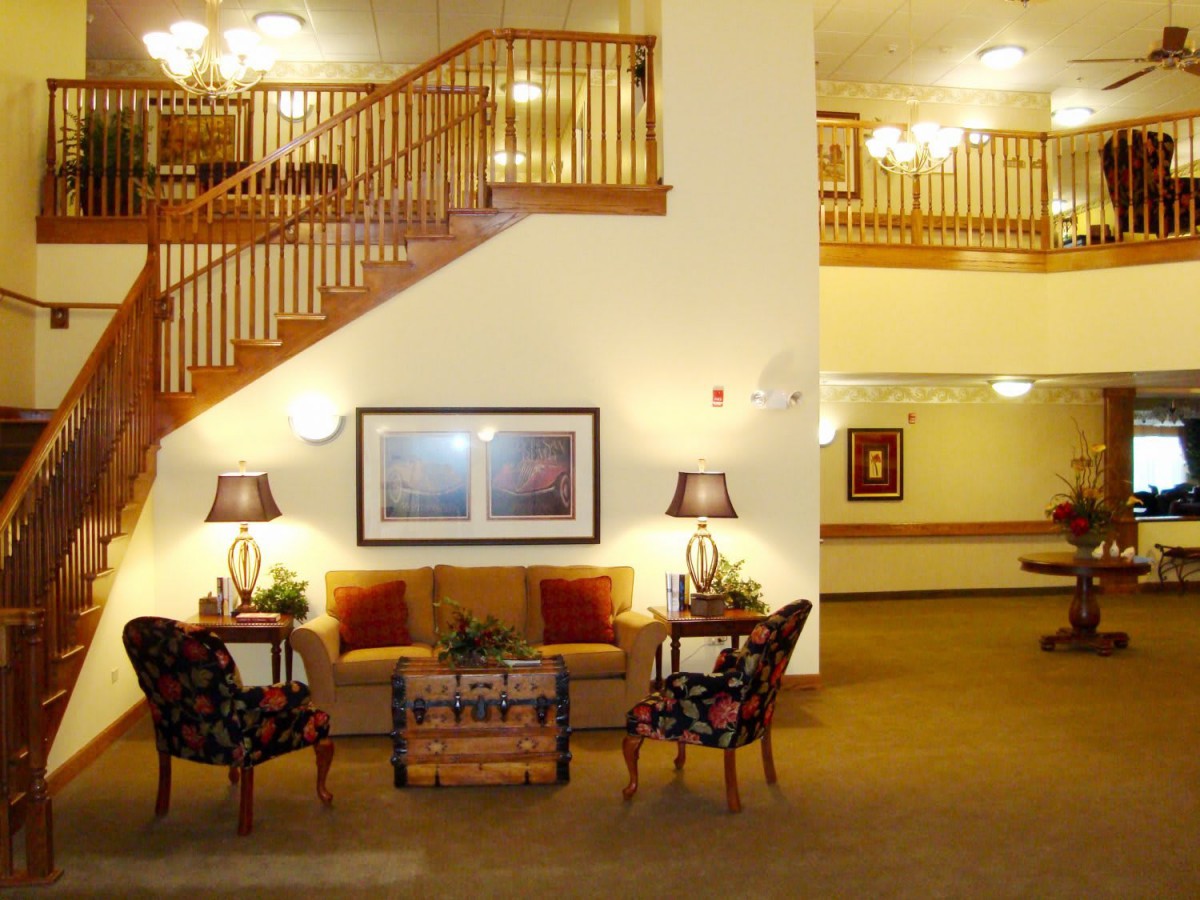 A well-lit lobby featuring comfortable seating and wooden stairs.