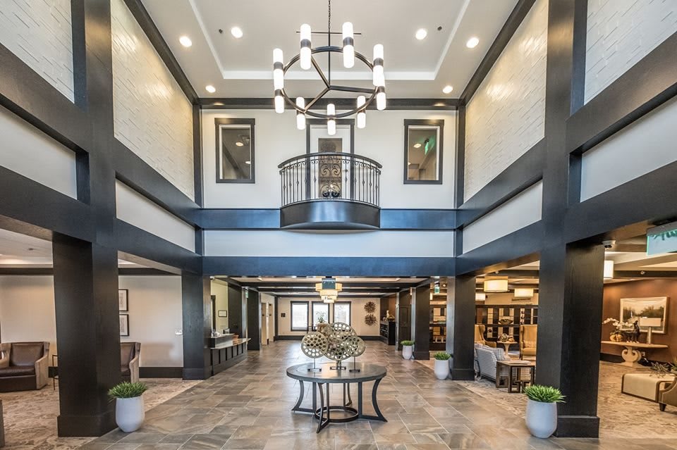 A spacious and elegantly designed lobby with a modern chandelier, featuring a central table and seating area.