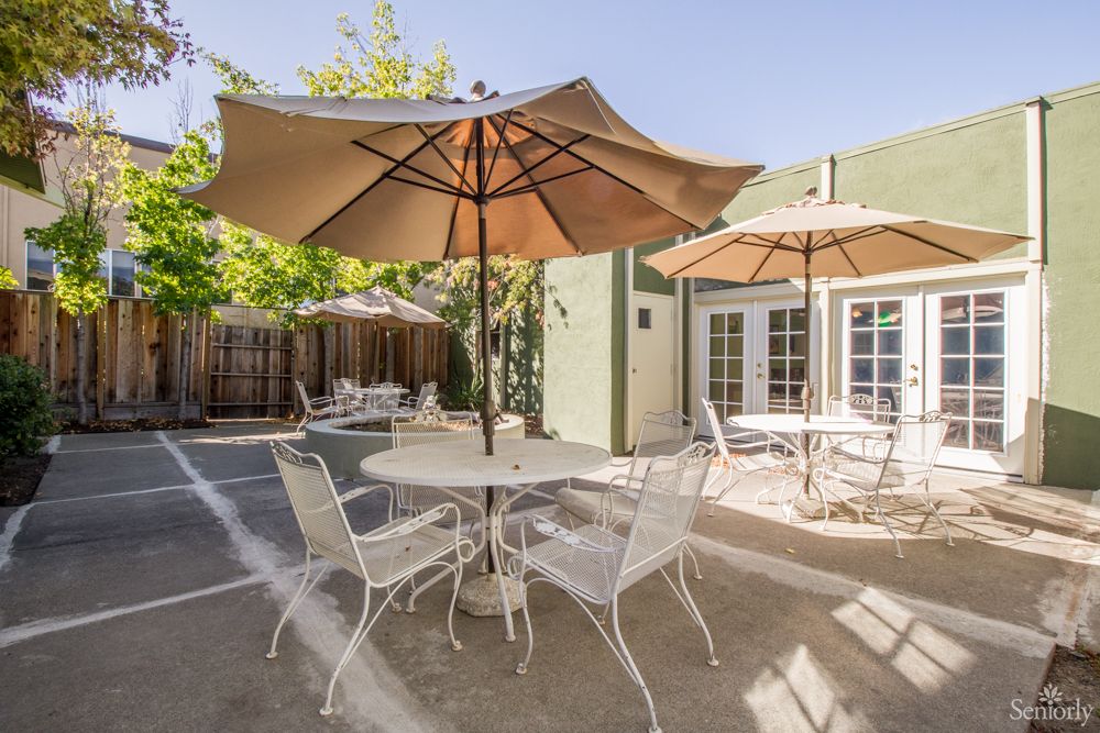 A sunny outdoor patio with tables, chairs, and umbrellas.
