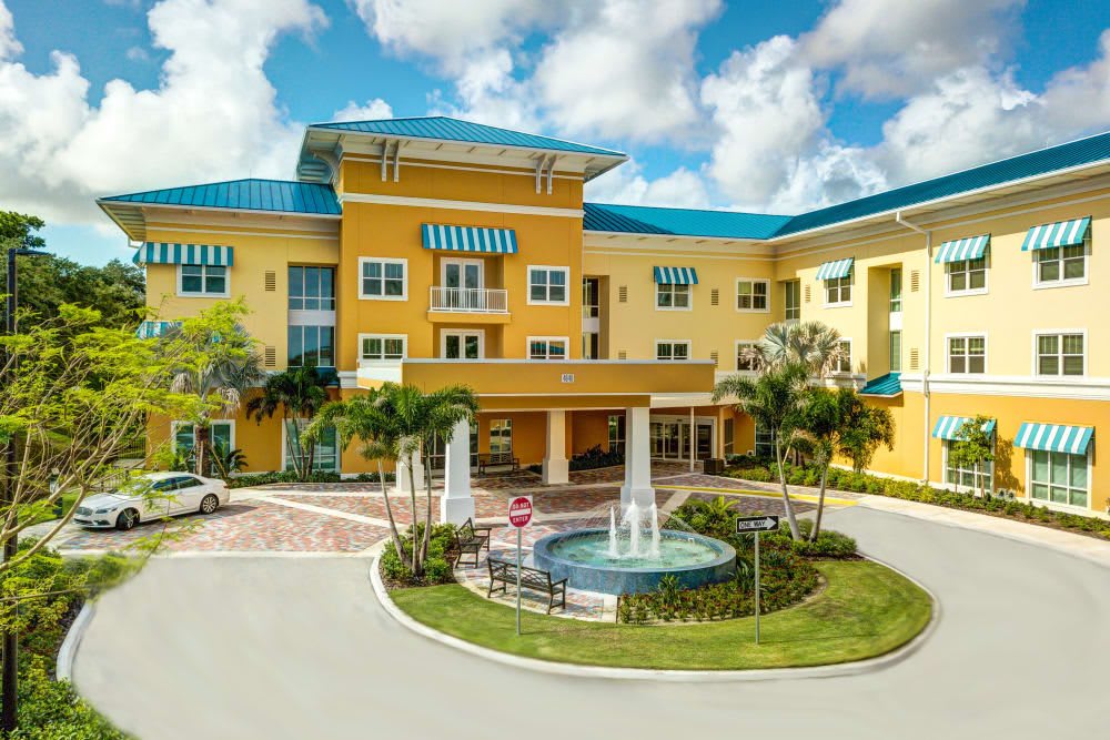 A vibrant, tropical-style residential building with a central fountain and palm trees.