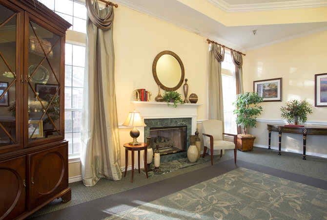 A traditional living room with a fireplace, elegant curtains, and classic furniture.