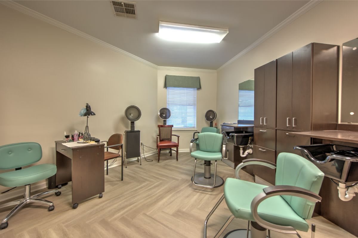 A cozy salon room featuring chairs, hair dryers, and a desk.