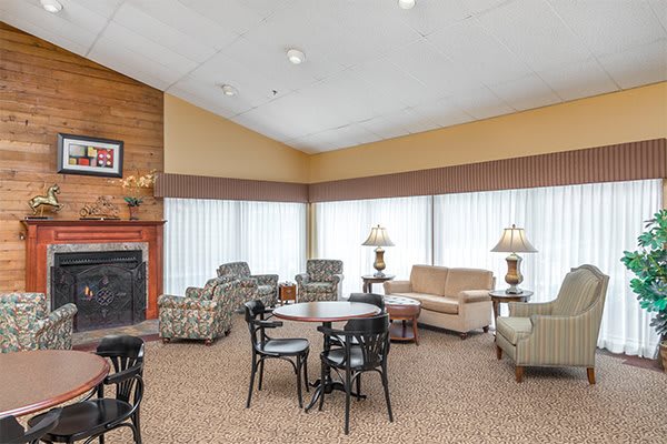 A cozy living room with comfortable seating, a fireplace, and tables.