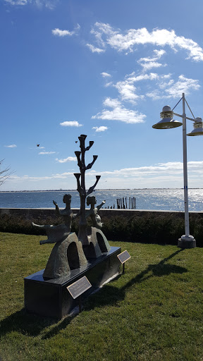 A beautiful sculpture by the waterfront under a clear blue sky.