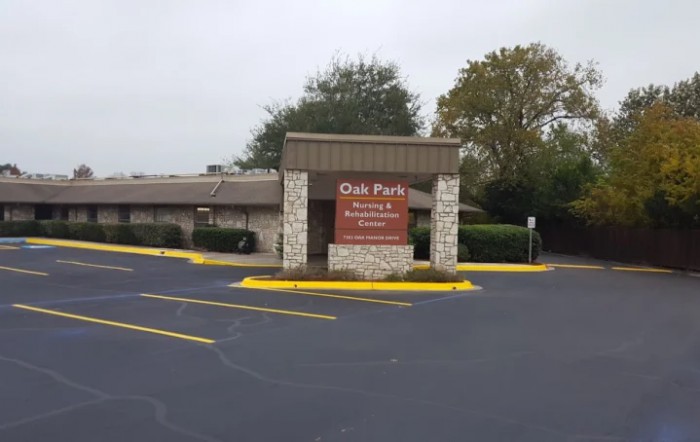An entrance to Oak Farms Dairy with a visible sign and adjacent parking lot.