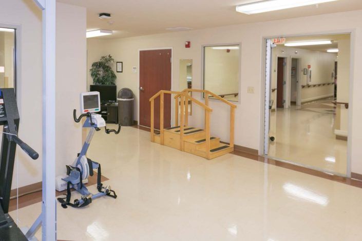 A clean and organized rehabilitation room with exercise equipment and therapy stairs.
