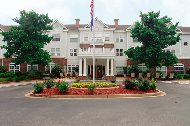 A hotel entrance with neatly landscaped surroundings and an American flag on display.