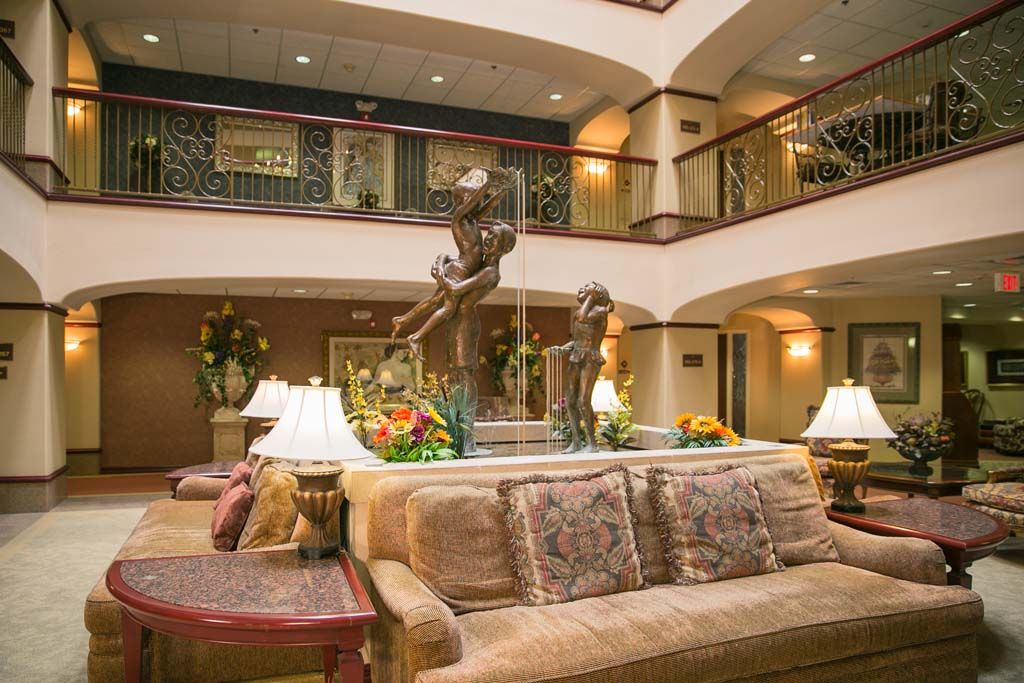 A luxurious hotel lobby featuring comfortable seating, elegant decor, and a central fountain.