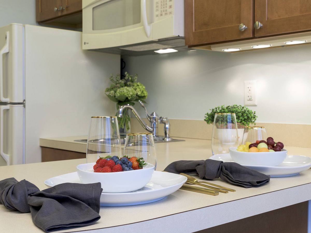 A modern kitchen countertop with a stylish dining setup, featuring fresh fruits and decorative plants.