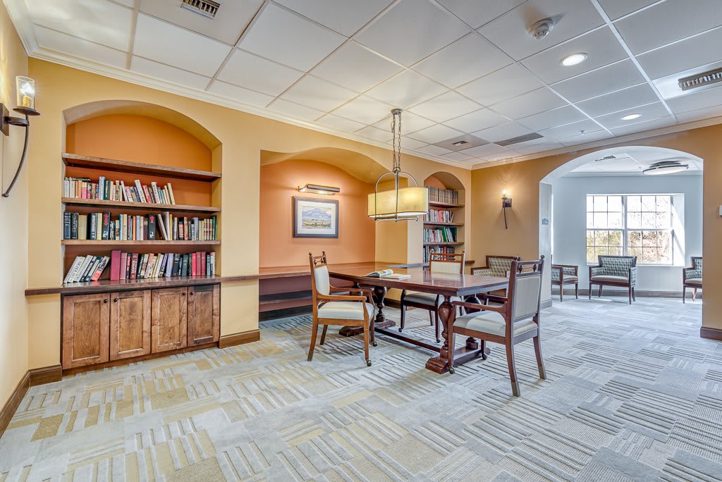 A cozy library reading area with bookshelves, a table, and chairs.
