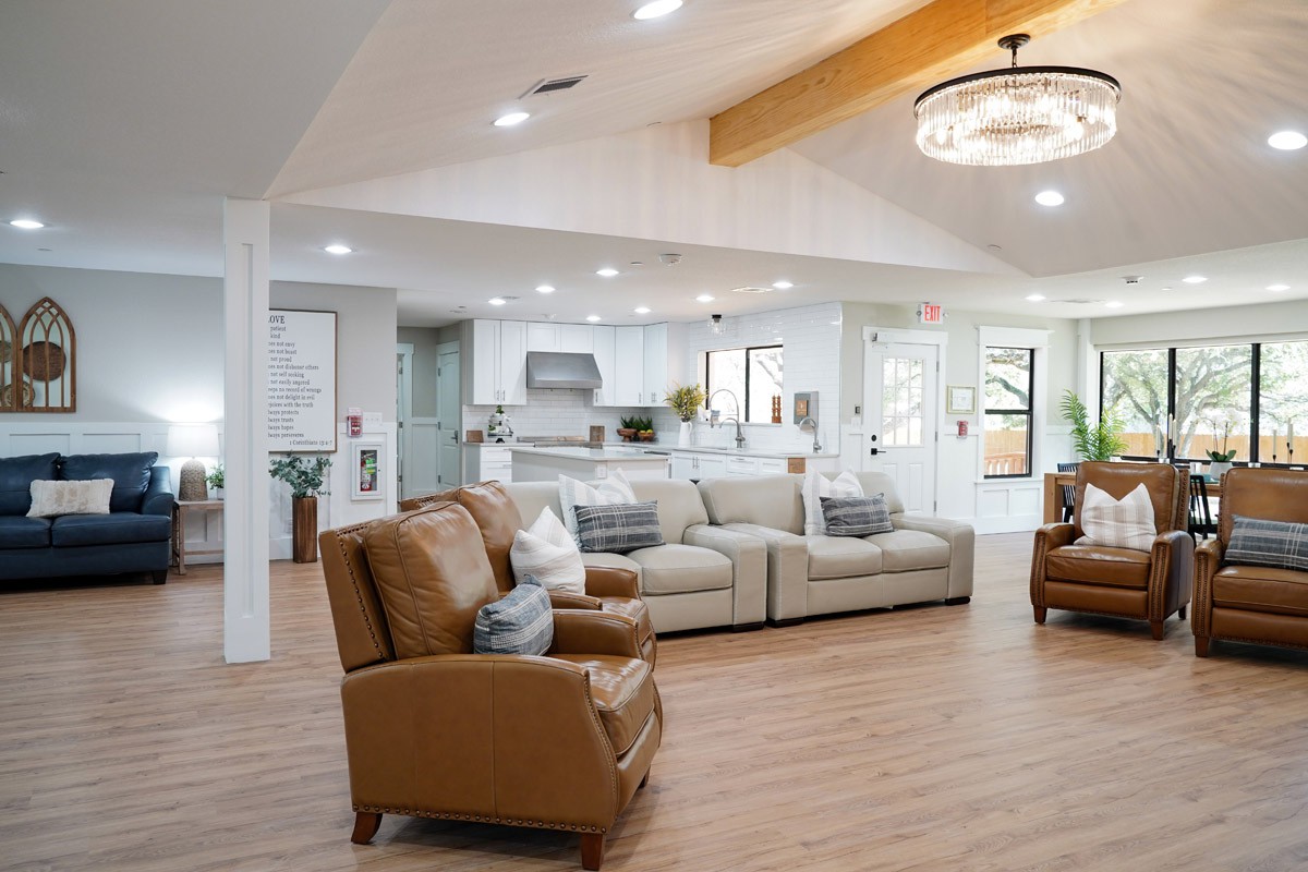 A modern open-concept living room and kitchen area with neutral tones, featuring comfortable seating and stylish lighting.