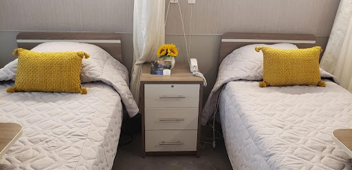 A serene bedroom featuring twin beds with a stylish nightstand adorned with colorful flowers.