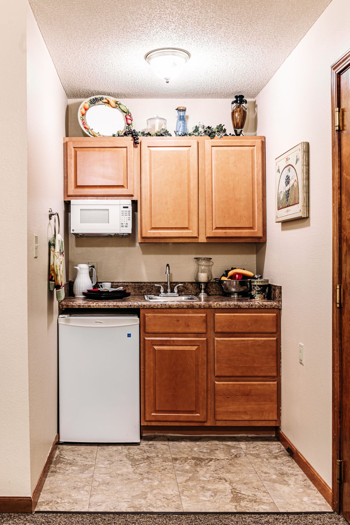 A compact kitchen area with wooden cabinets, a mini fridge, and a microwave.