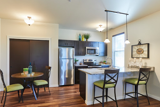 A modern kitchen featuring stainless steel appliances, dark cabinetry, and a cozy dining area.