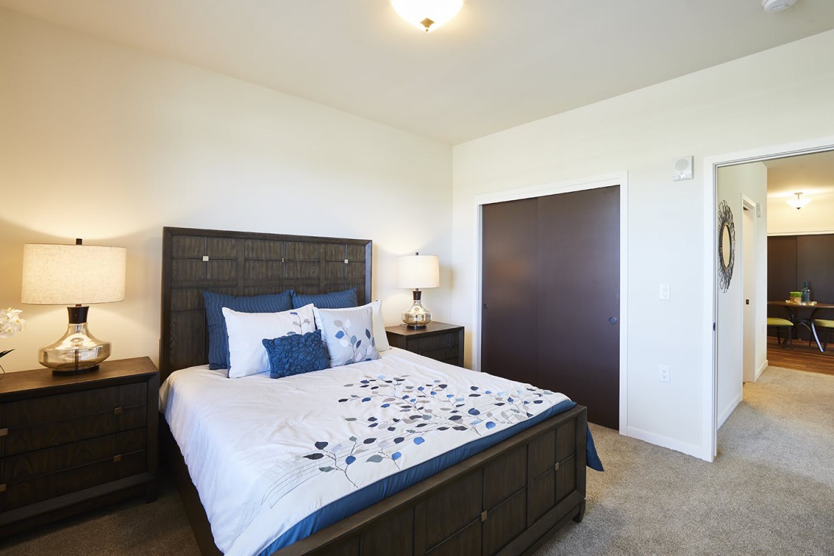 A neatly arranged bedroom with a bed, nightstand, and lamp.
