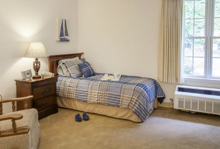 A cozy bedroom with a single bed, nightstand, and a lamp.
