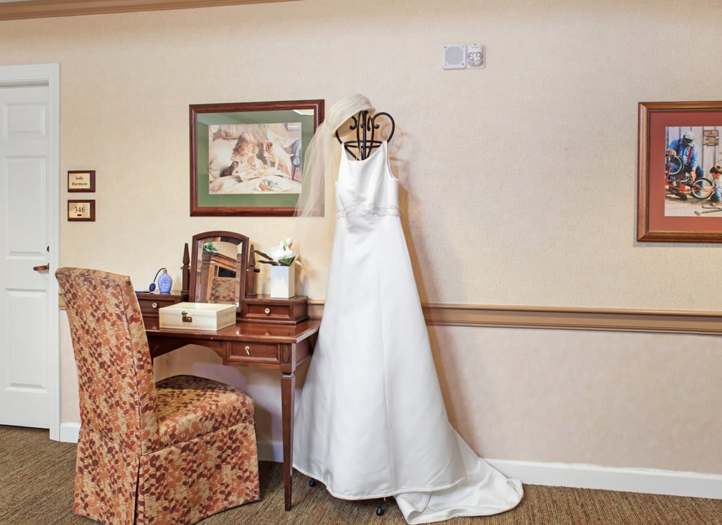 A wedding dress elegantly displayed on a mannequin next to a vanity table in a cozy room.