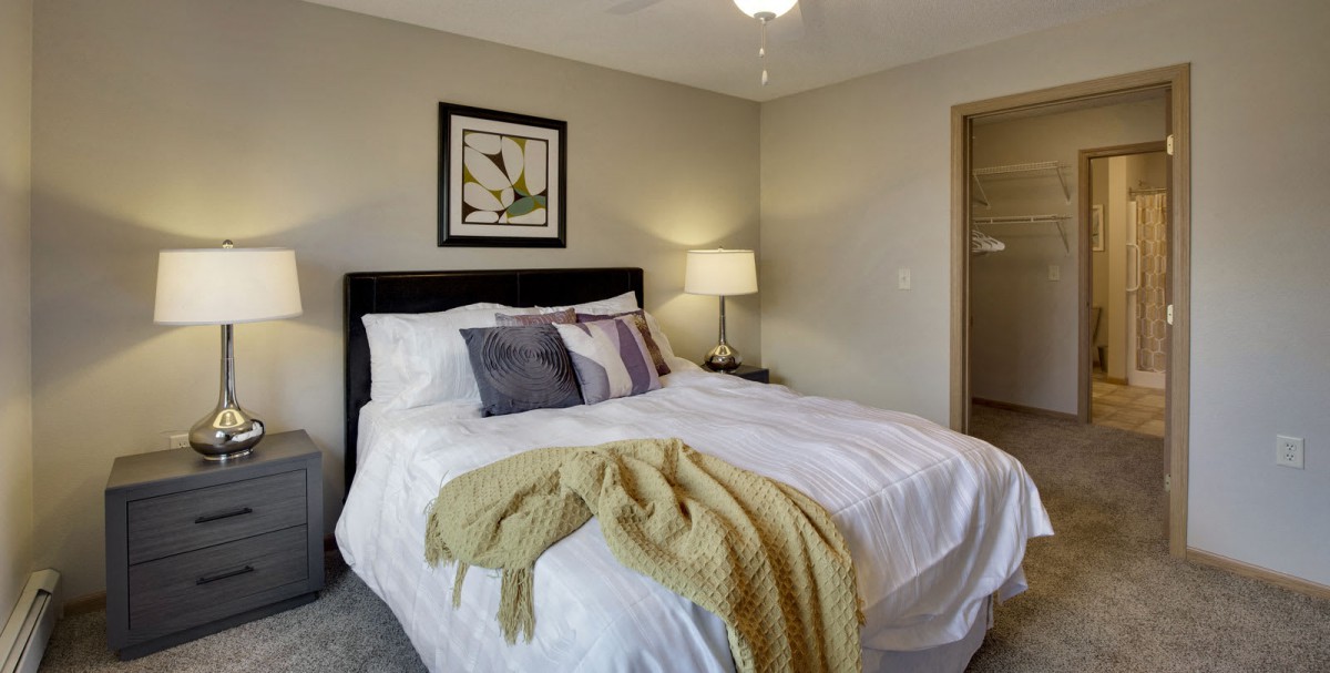 A modern and cozy bedroom interior with a neatly made bed, decorative pillows, and a stylish lamp.