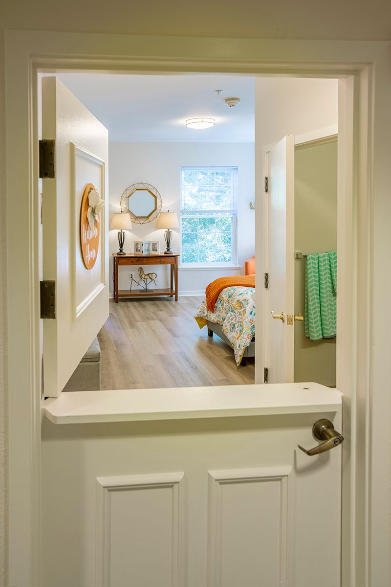 A view through an open doorway into a cozy bedroom featuring bright decor and natural lighting.