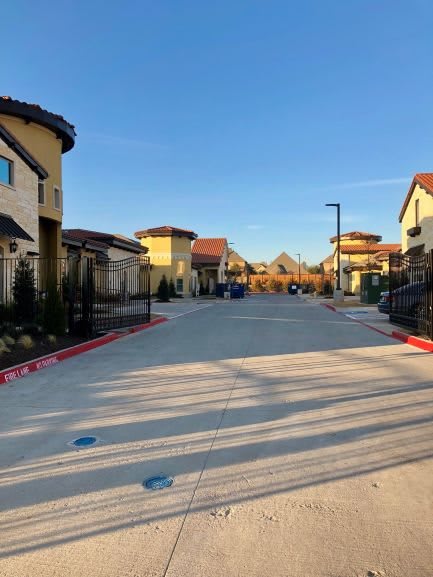 A quiet suburban street lined with modern houses under a clear blue sky.