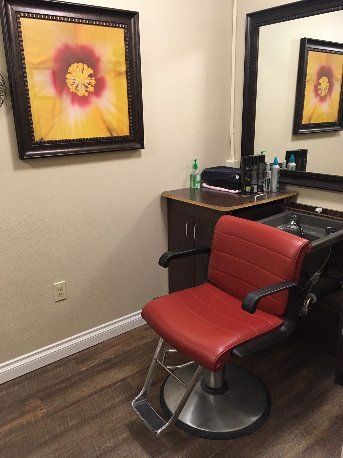 A cozy hair salon setup with a red chair and mirror, accented by vibrant wall art.