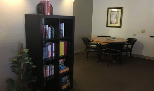 A cozy reading nook with a bookshelf filled with books and a workspace featuring a table and chairs.