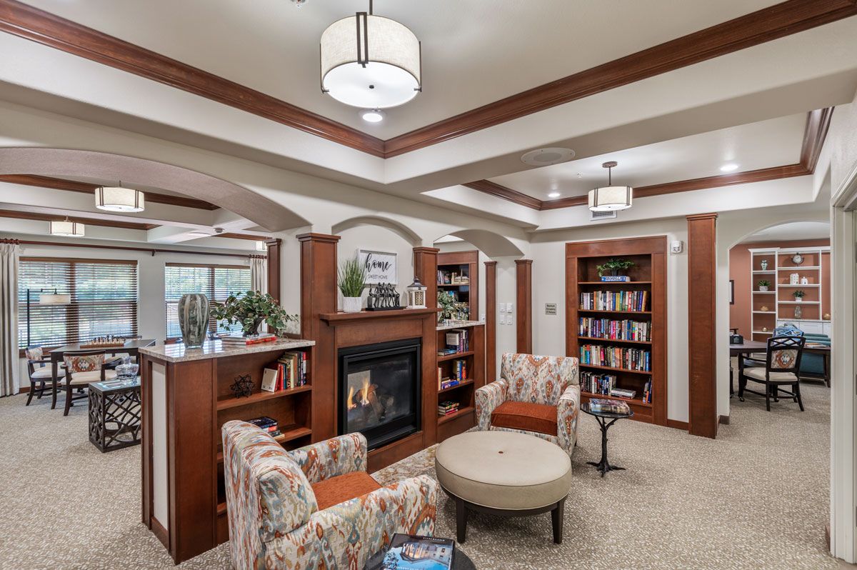 Cozy library interior with bookshelves, a fireplace, and comfortable seating.