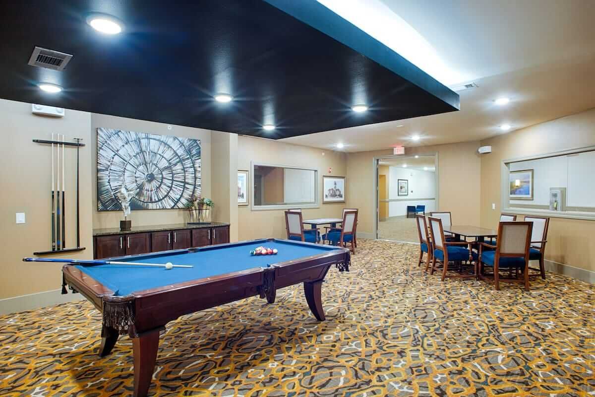 A recreation room featuring a pool table, carpeted flooring, and modern artwork on the walls.