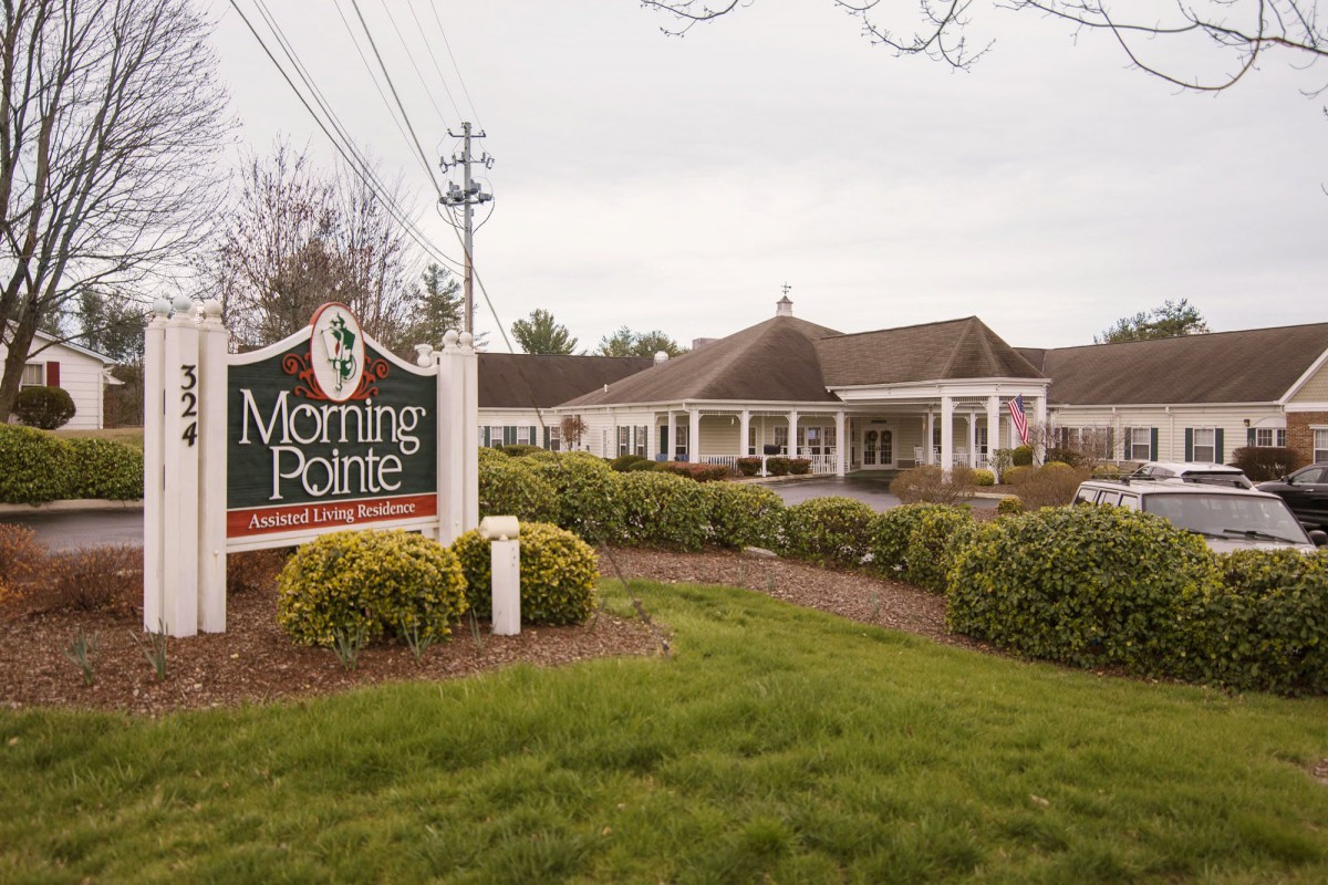 A view of an assisted living facility with a sign reading 'Morning Pointe' surrounded by well-maintained landscaping.