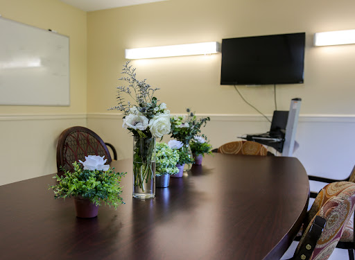 A well-decorated conference room featuring a wooden table adorned with floral arrangements, a television for presentations, and a warm ambiance.