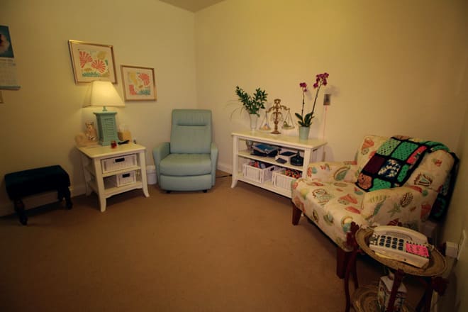 A cozy living room with a light blue armchair, decorated tables, and warm lighting.